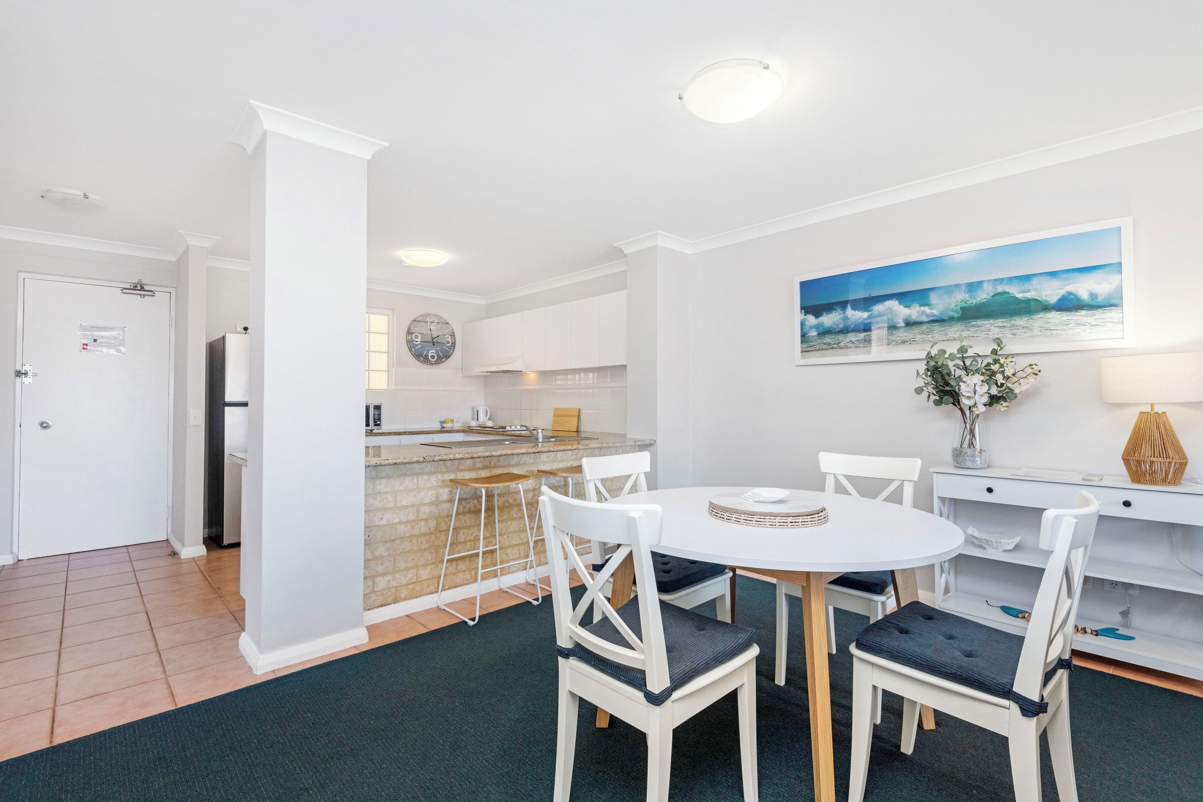 A modern kitchen with white cabinets, a built-in oven, and a stainless steel refrigerator.