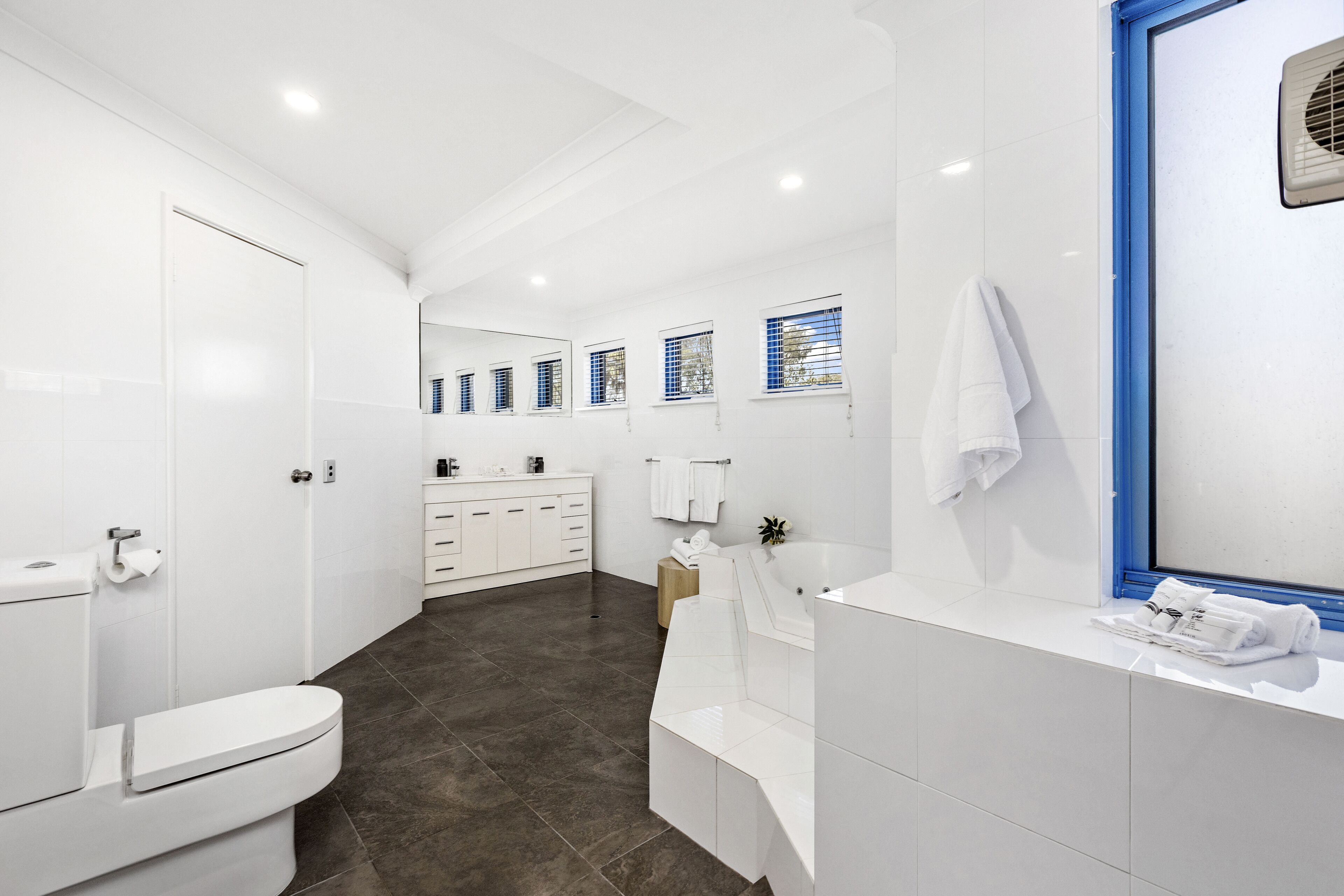 A modern bathroom with a toilet, sink, bathtub, and shower area.