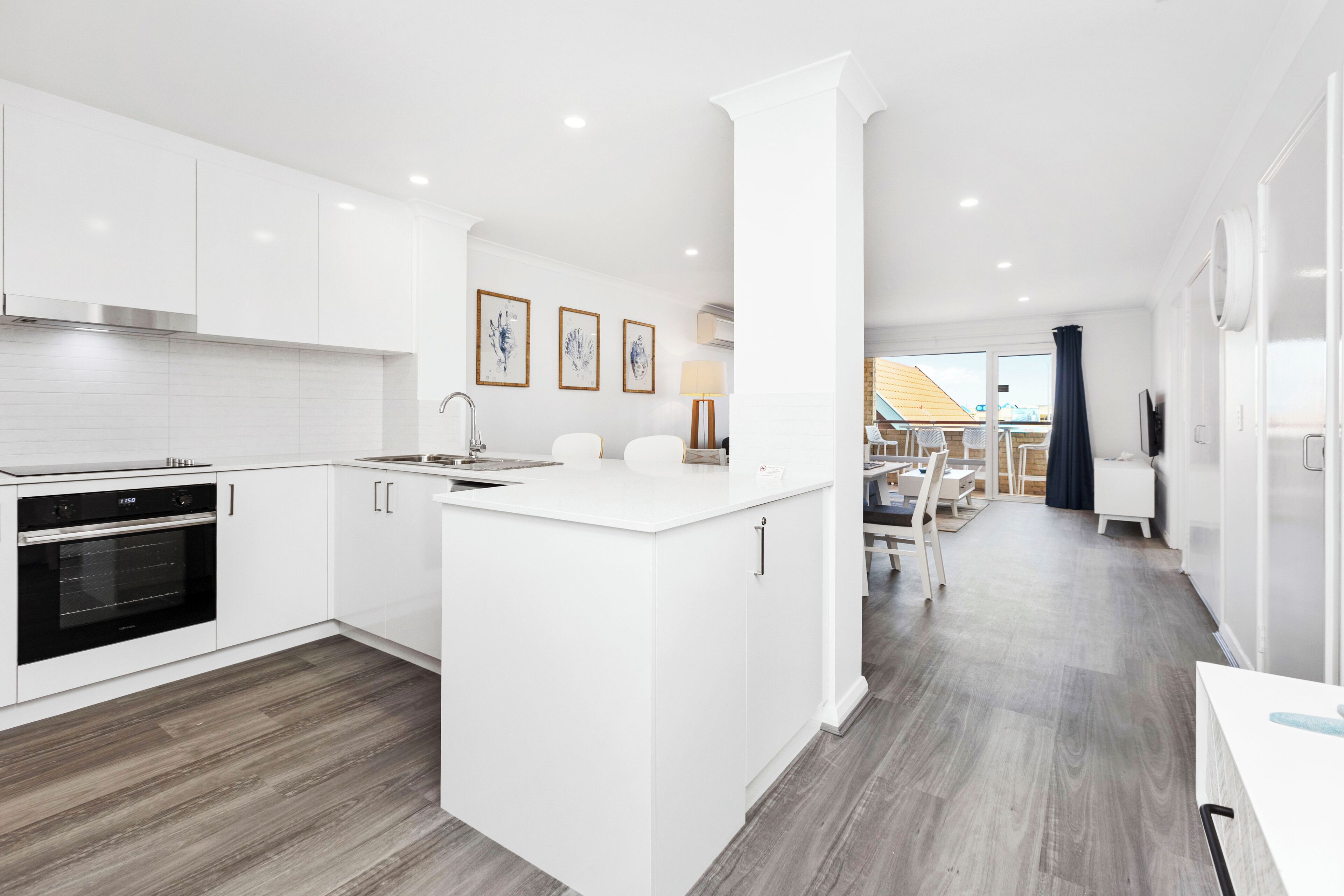 A modern kitchen with white cabinetry, a central island, and a dining area with a view.
