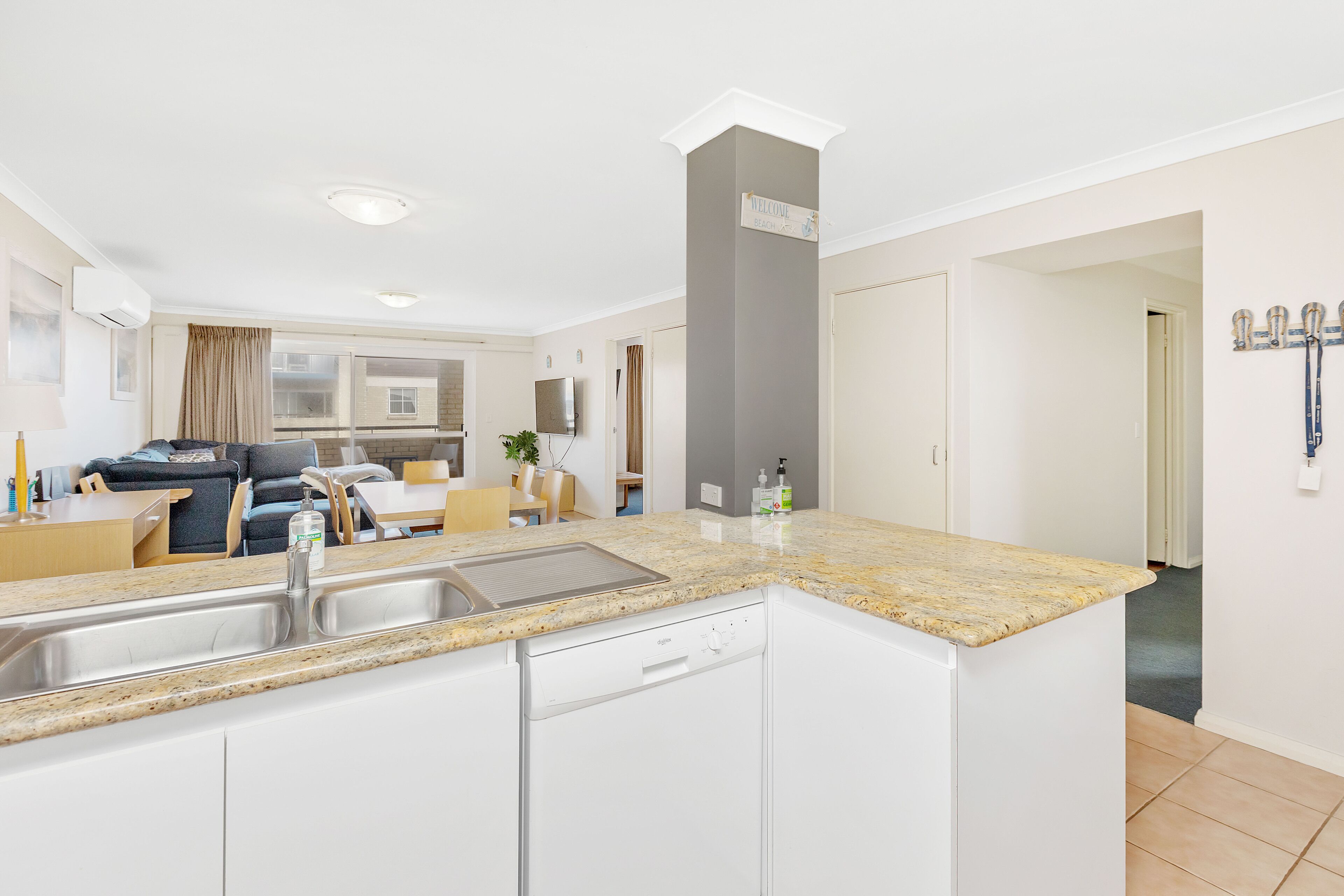 A modern kitchen with white cabinets, a granite countertop, and a built-in dishwasher.