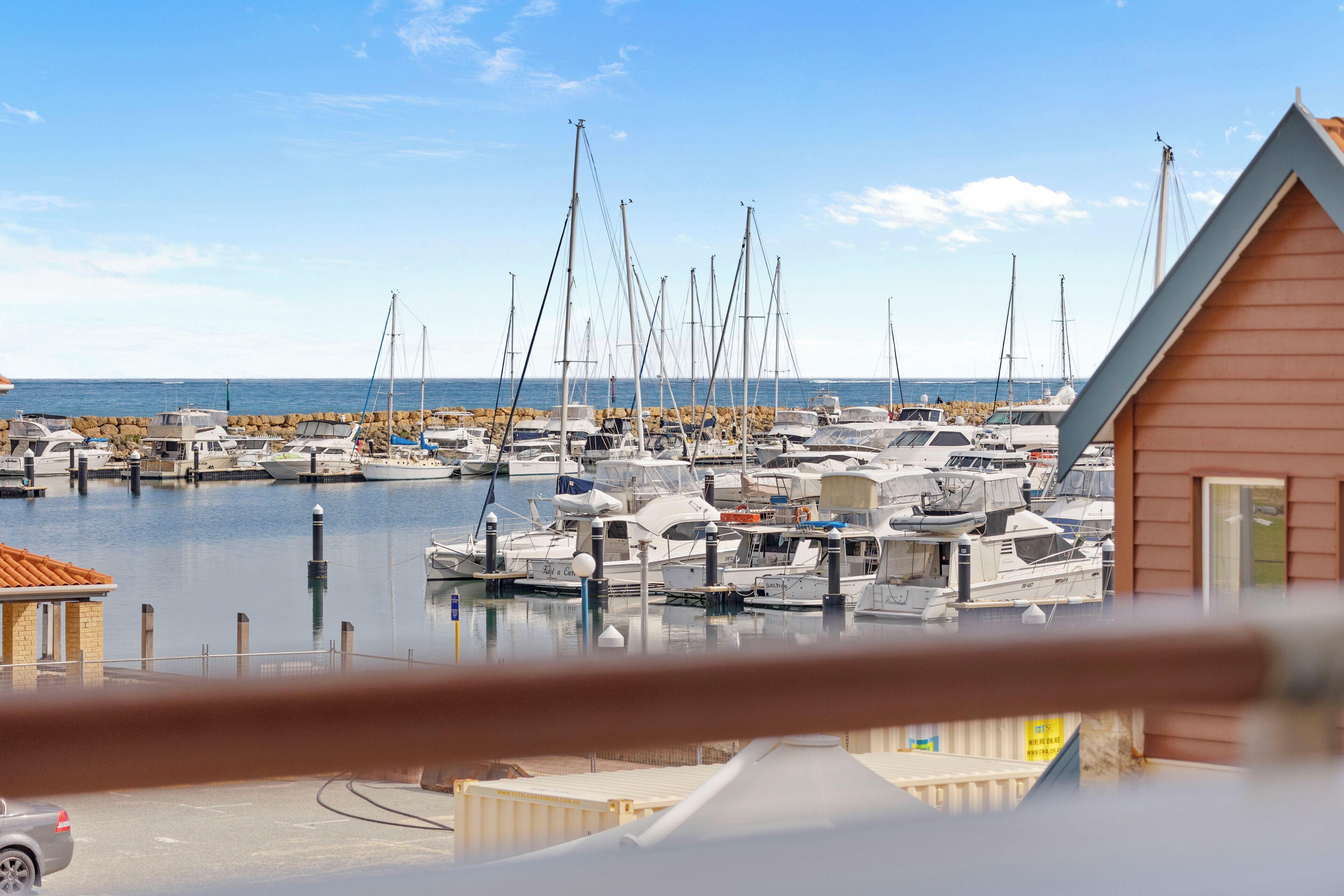 A marina with boats docked, a wooden building, and a clear sky.