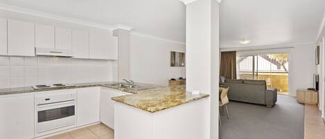 A modern kitchen with white cabinetry, a granite countertop, and a built-in oven.