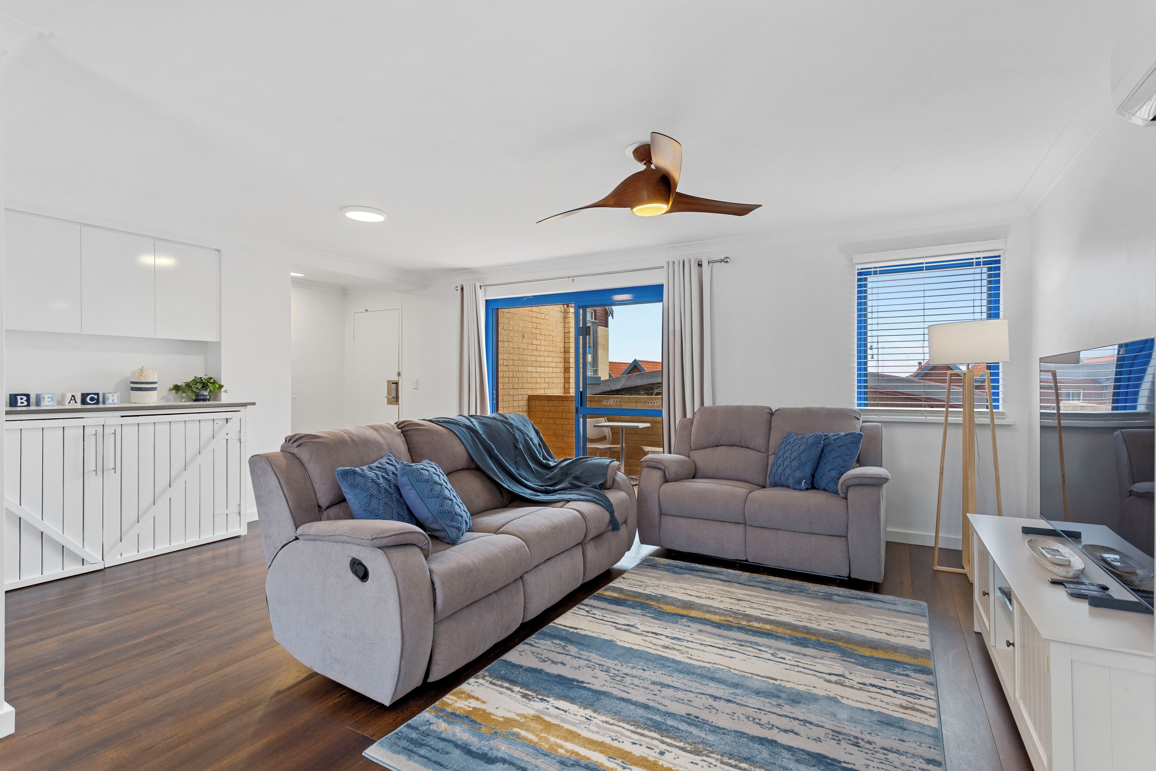 A modern living room with a sofa, armchair, and a ceiling fan.