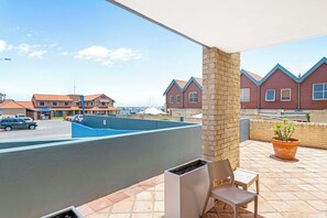 A balcony with a view of a swimming pool, a chair, and a potted plant. - Nautica Residences Hillarys (Hillarys)