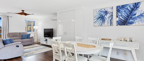 Ein modernes Wohnzimmer mit einer Couch, Fernseher, Esstisch und Stühlen.