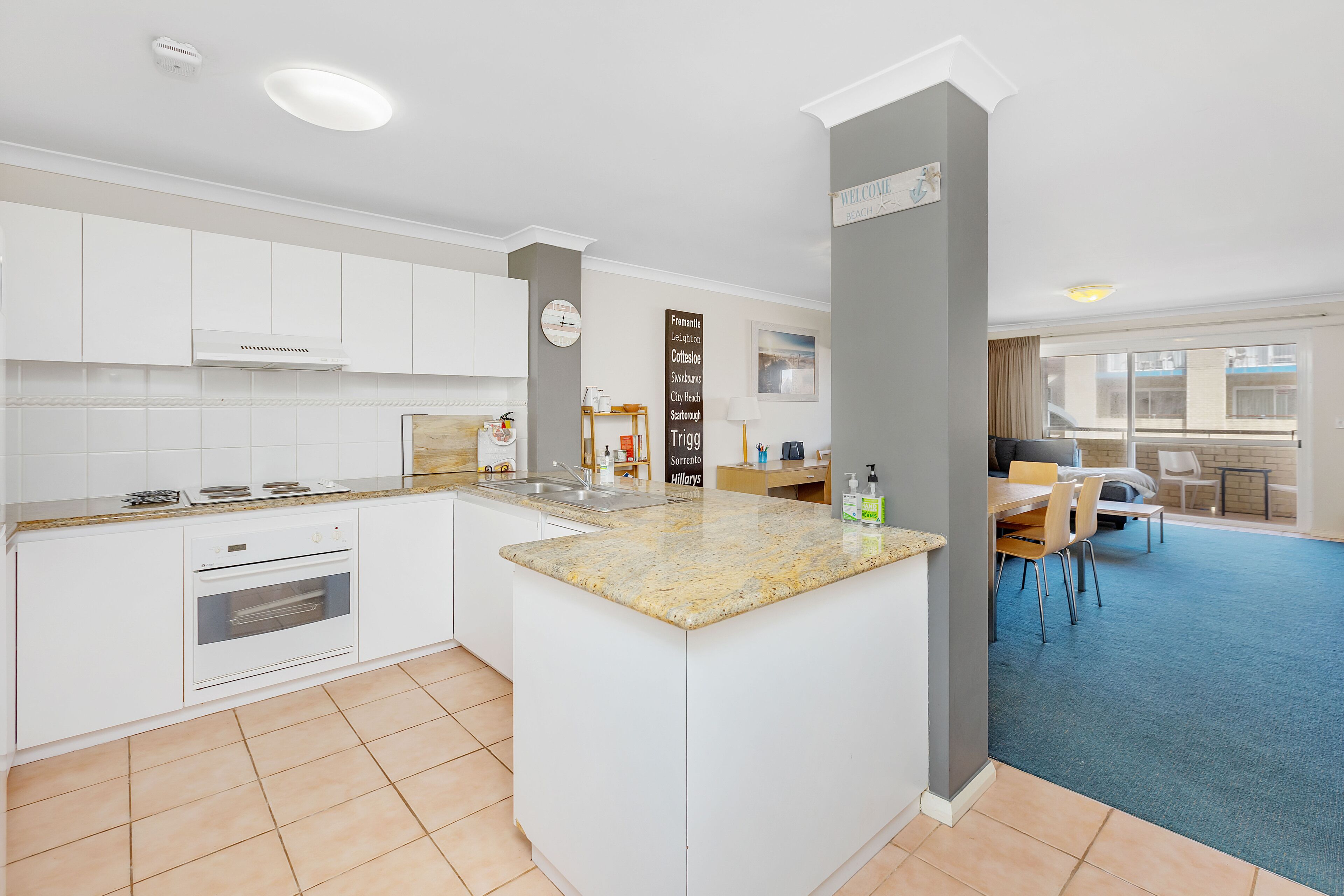 A modern kitchen with white cabinets, a granite countertop, and a built-in oven.