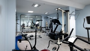 Uma academia com diversos equipamentos de exercício, um espelho e uma estátua.