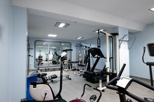 Un gimnasio con equipos de ejercicio variados, un espejo y una estatua.