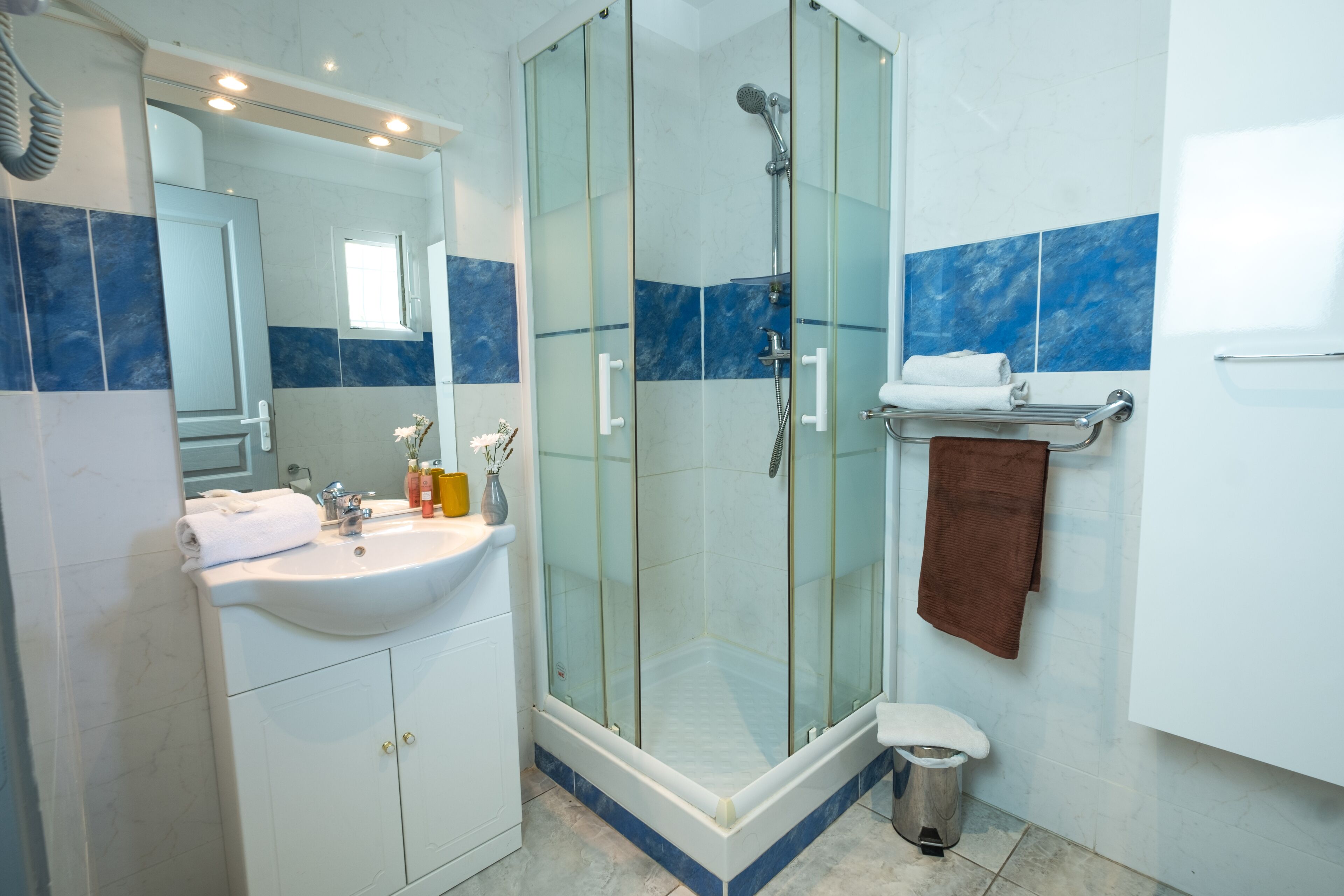 Ein modernes Badezimmer mit einer Duschkabine, einem Waschbecken mit Toilettenartikeln und einem Handtuchhalter.