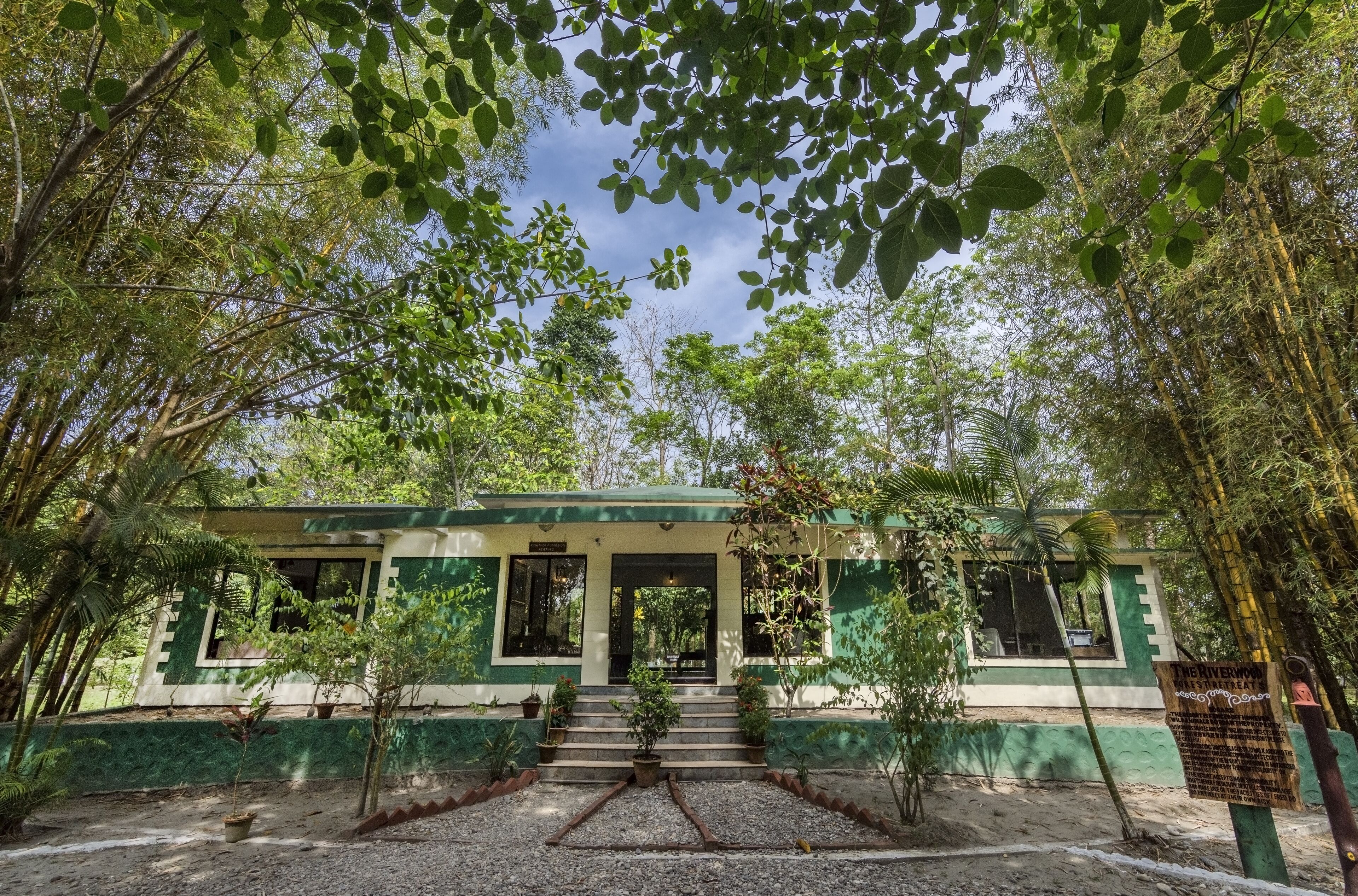A building with a green and white facade, a set of stairs leading to the entrance, and a signboard in the foreground.