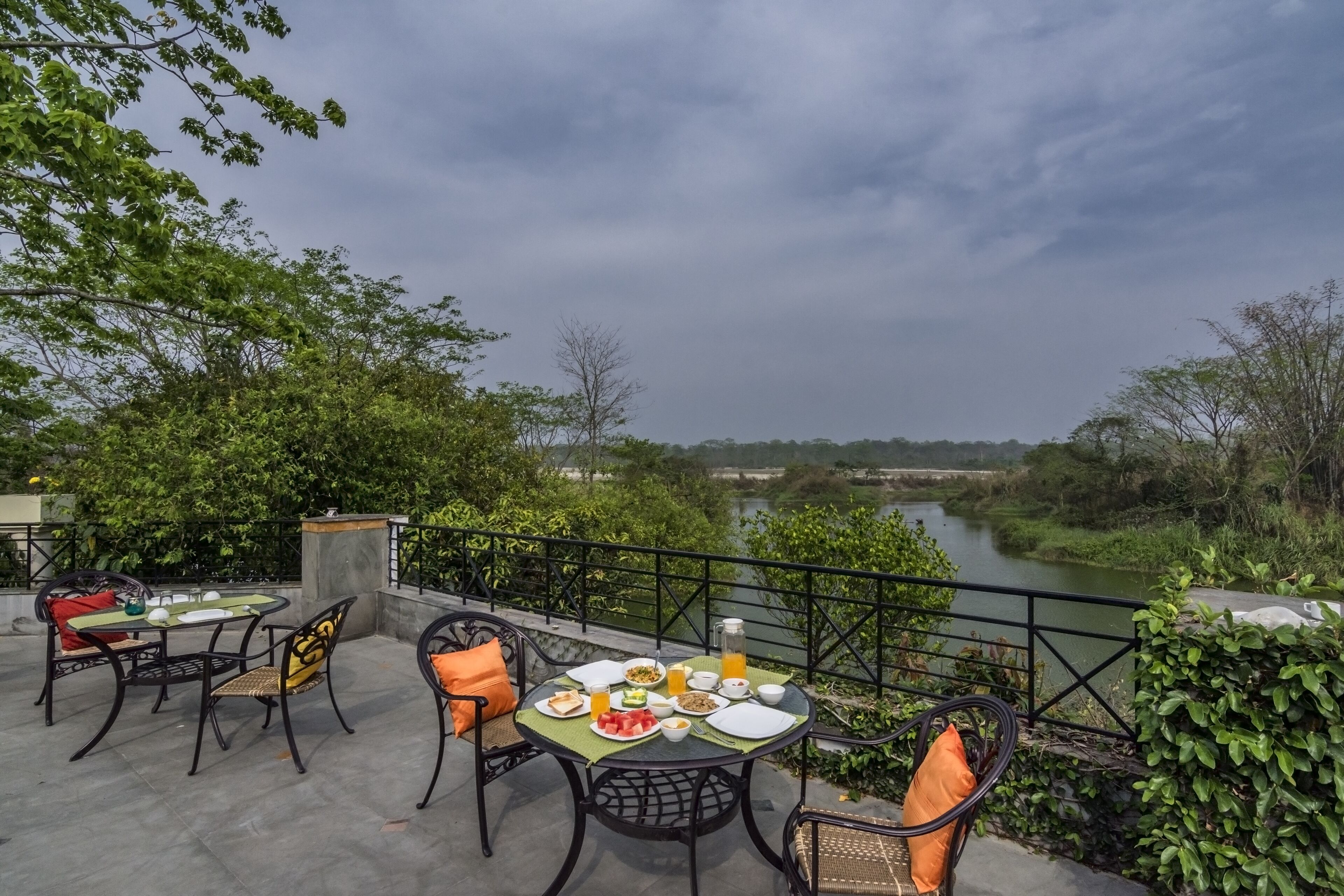 Un espace extérieur aménagé pour prendre les repas, avec une table dressée pour le petit-déjeuner, donnant sur une rivière.