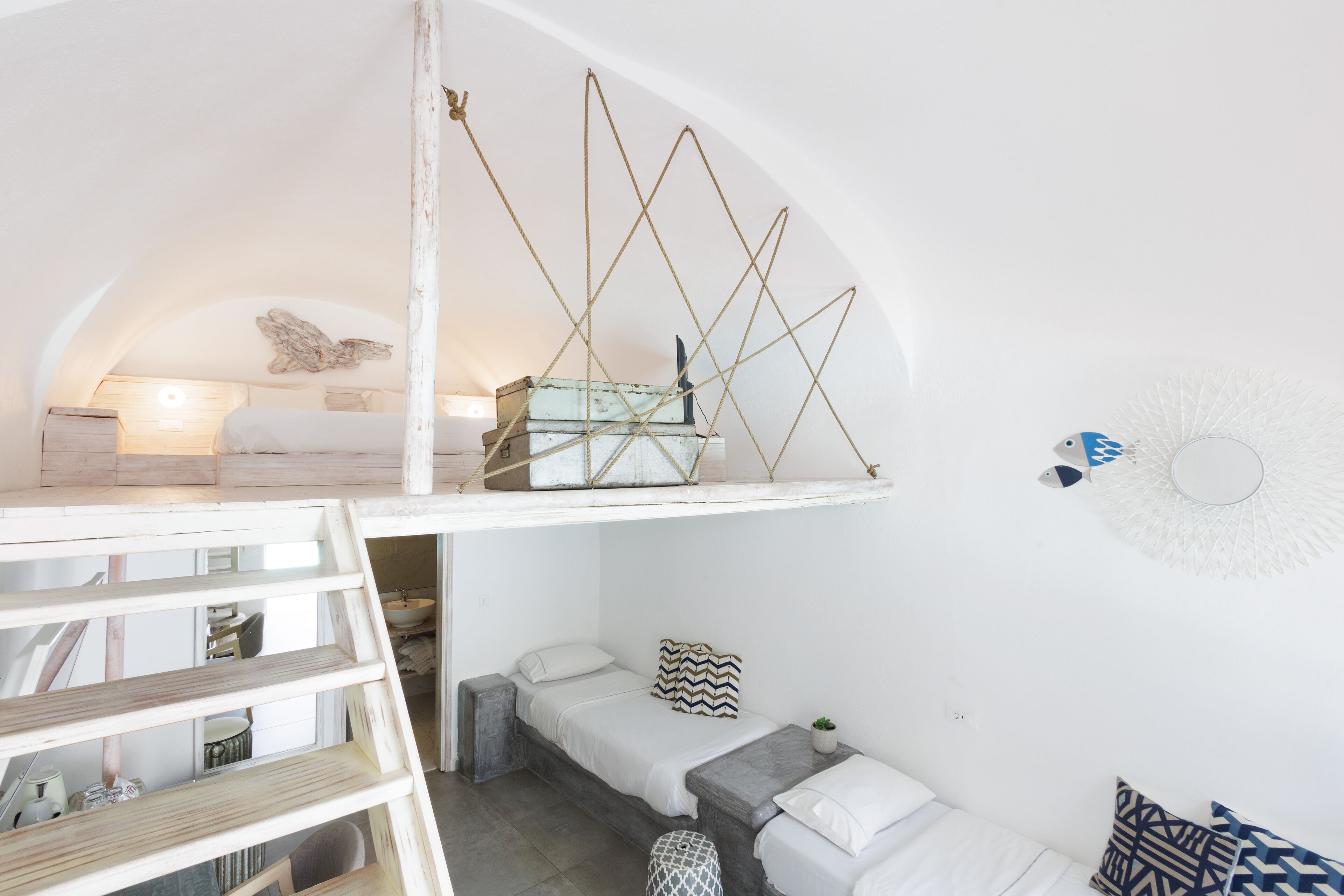 A compact, loft-style bedroom with a loft bed, a small seating area, and a decorative wall piece.