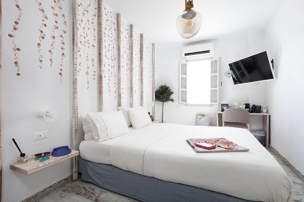 A modern hotel room with a large bed, a desk, and a mounted TV.