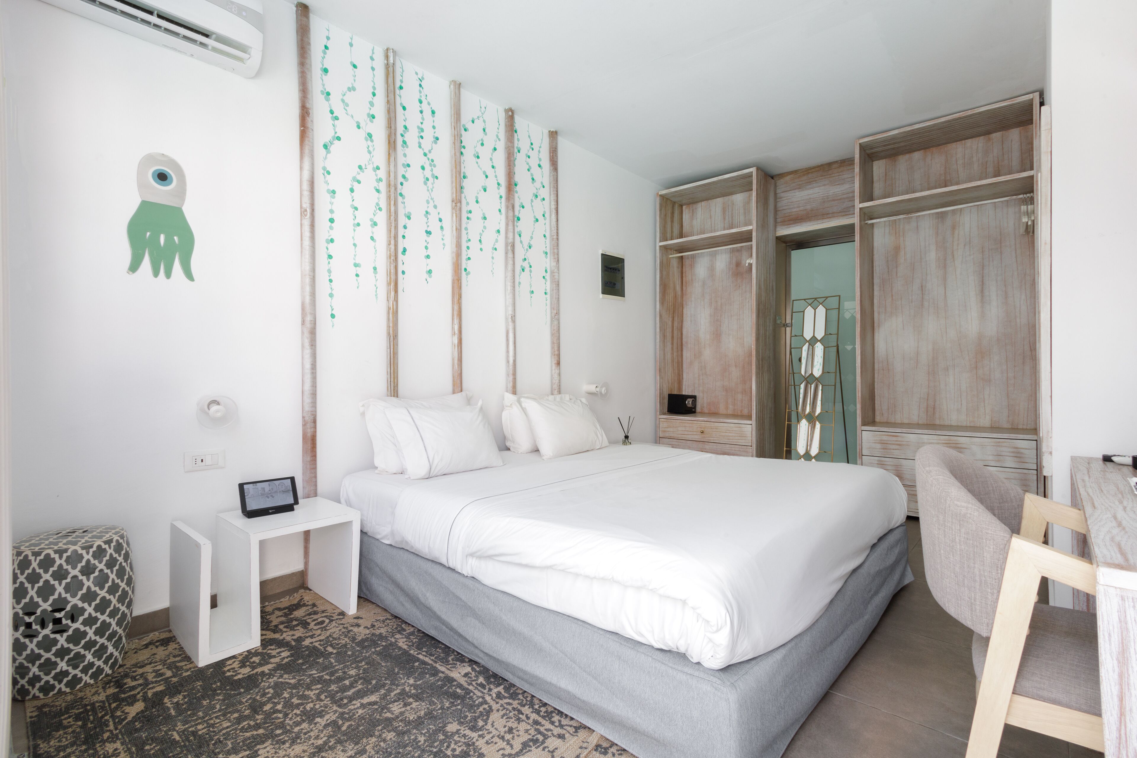 Una habitación de hotel moderna con una cama grande, un escritorio pequeño, una silla y un armario.