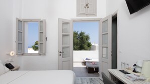 Une chambre à coucher avec un lit, une table de chevet et une vue sur un balcon équipé d’une table et de chaises.