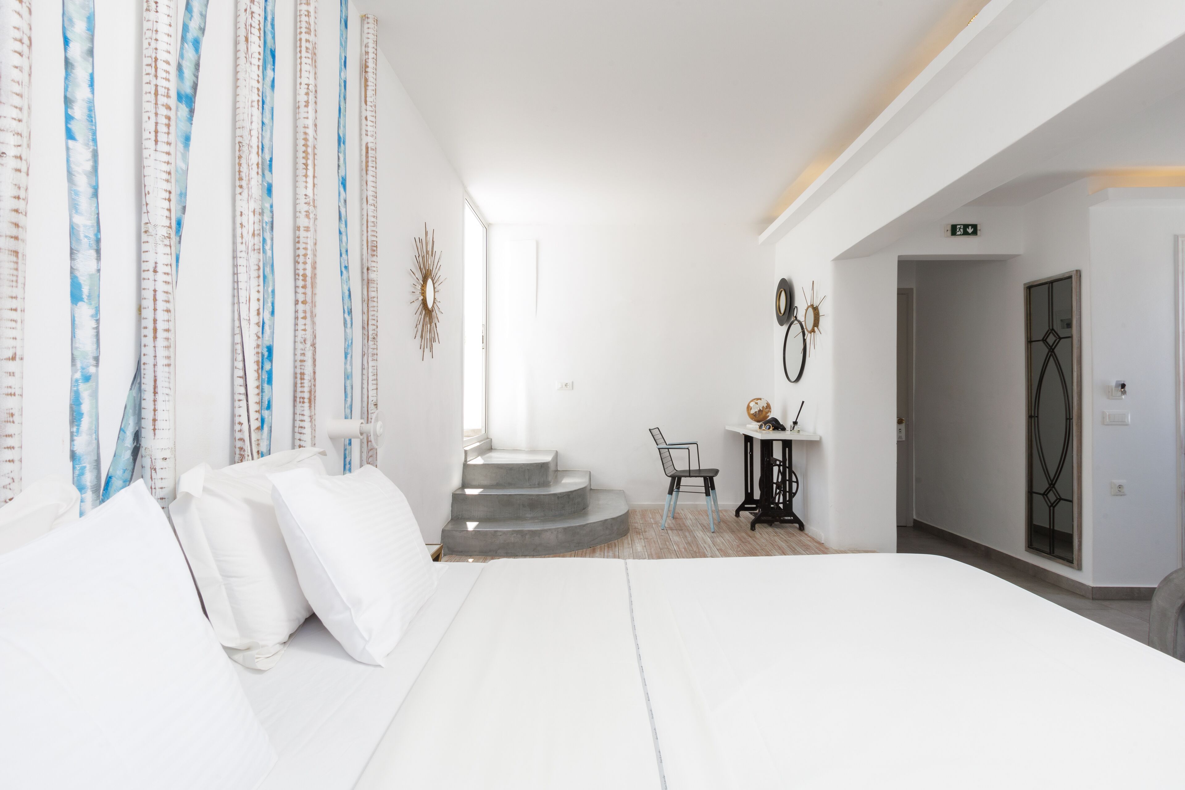 Habitación de hotel con cama, escritorio y silla. Se ven escaleras que conducen a otra habitación.