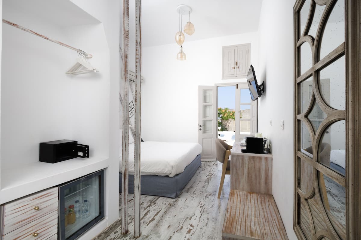A bedroom with a bed, a desk, a television, and a wardrobe.