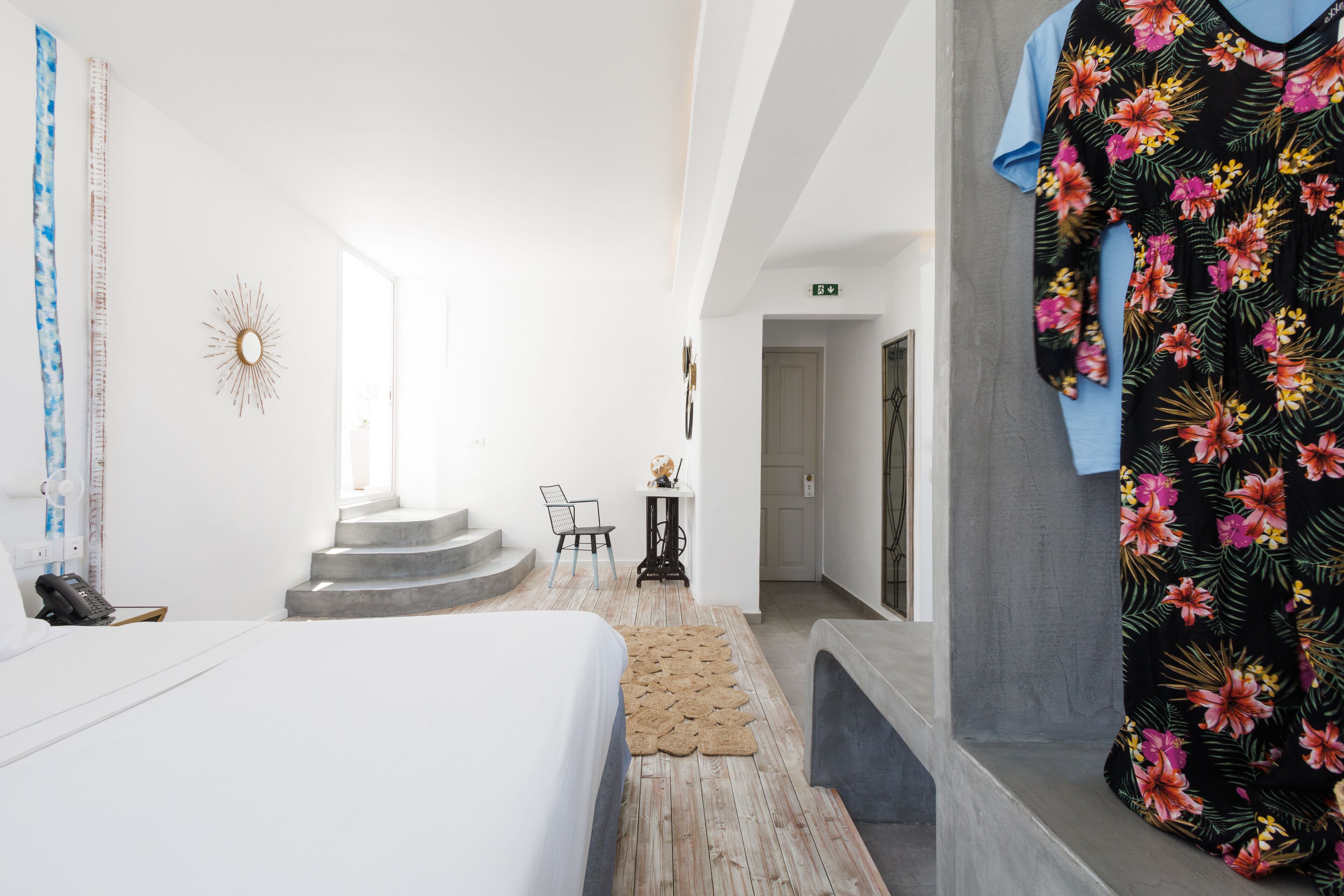 Habitación de hotel con cama, un pequeño escritorio, una silla y una escalera que lleva a otra habitación.