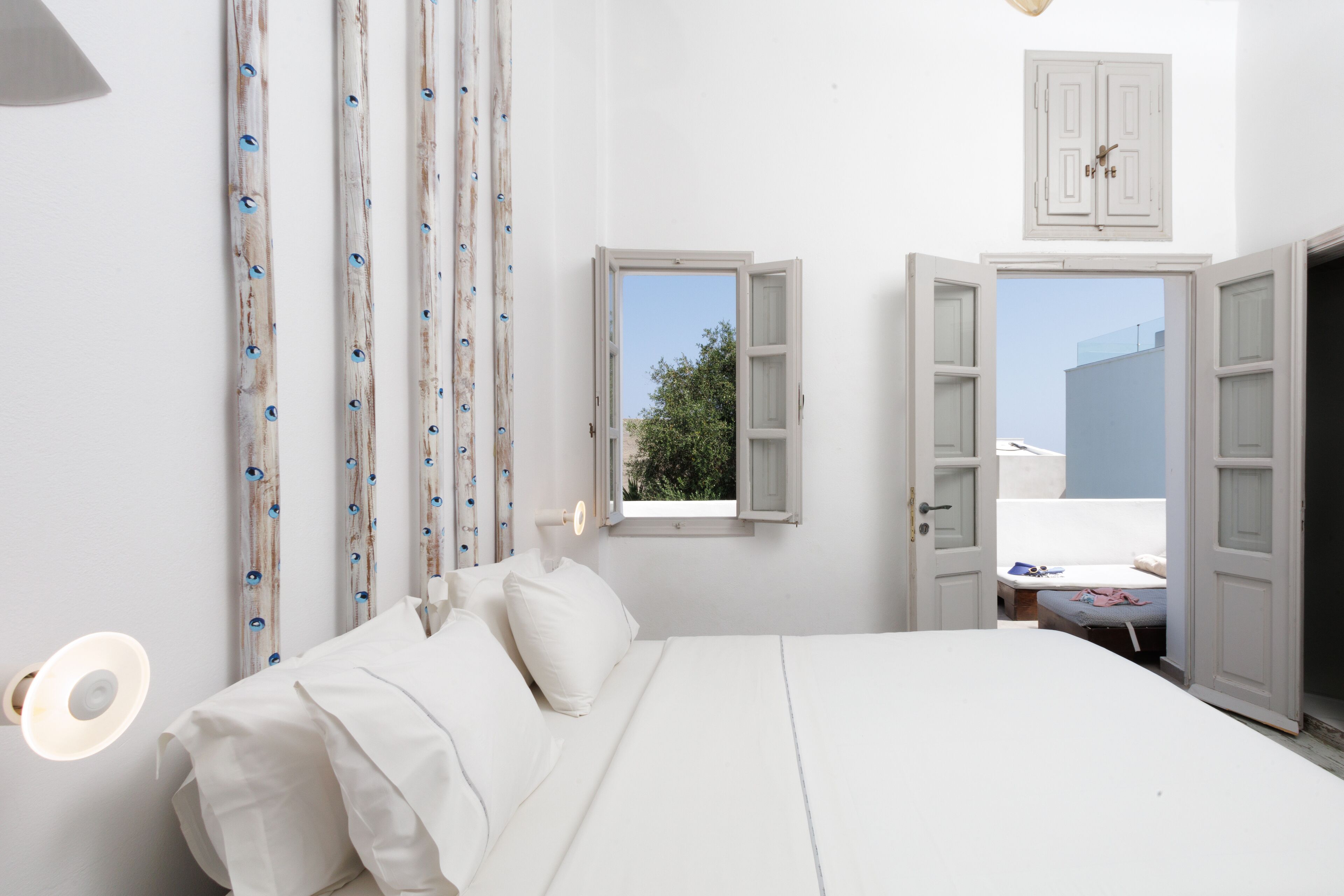 A bedroom with a bed, a window, and a door leading to another room.