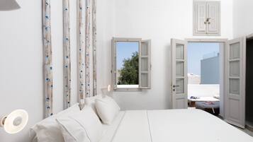 A bedroom with a bed, a window, and a door leading to another room.