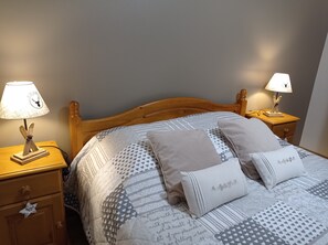 A neatly made bed with patterned bedding, two bedside lamps, and a wooden nightstand with a drawer. - Les Agapanthes *** Lakeside Apartment (Gérardmer)