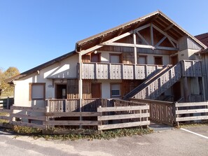 Ein zweistöckiges Holzhaus mit Balkon und einer Treppe, die zum Obergeschoss führt.