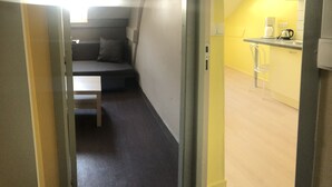 Une chambre de taille modeste comprenant un lit, une petite table et un coin cuisine équipé d’une machine à café.