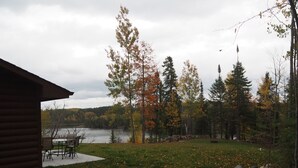 A cabin with a patio overlooking a lake, surrounded by trees with autumn foliage. - Enjoy privacy in this newly built cabin with spectacular view of North Star Lake (Marcell)
