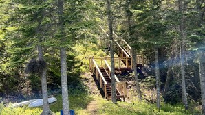 A wooden staircase leading up to a platform in a forested area with a small dock extending into a body of water. - Enjoy privacy in this newly built cabin with spectacular view of North Star Lake (Marcell)