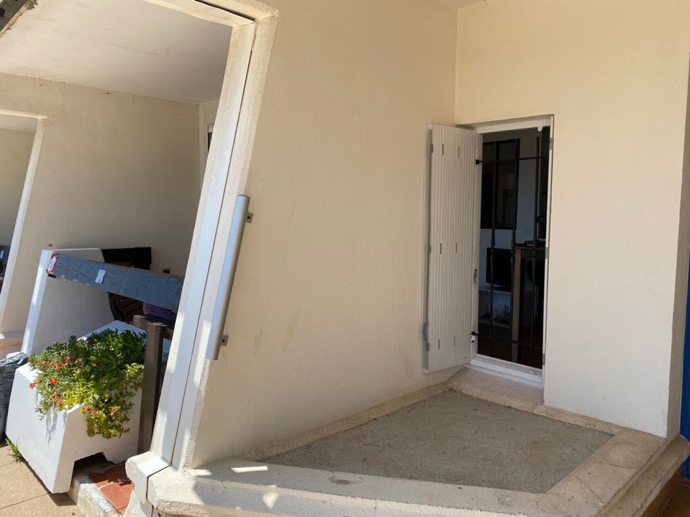 Un balcón pequeño y cerrado con una puerta blanca y suelo de hormigón.