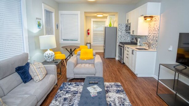 A compact living space with a sofa, armchair, coffee table, and a kitchenette.