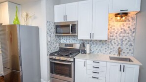 A modern kitchen with white cabinets, stainless steel appliances, and a patterned backsplash.