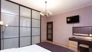 A modern bedroom with a large bed, a desk with a chair, a television, and a sliding glass door. - MinskLux Apartments 2 bedrooms - 100 sqm (Minsk)