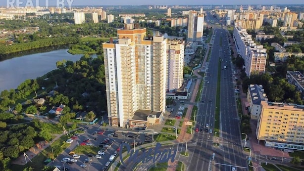 A high-rise building with multiple floors, surrounded by a cityscape with roads and greenery. - MinskLux Apartments 2 bedrooms - 100 sqm (Minsk)