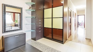 A modern hallway with a dark wooden wardrobe, a glass shelf unit, and a large mirror. - MinskLux Apartments 2 bedrooms - 100 sqm (Minsk)