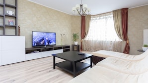 A modern living room with a flat-screen TV, a black coffee table, a white sofa, and a bookshelf. - MinskLux Apartments 2 bedrooms - 100 sqm (Minsk)