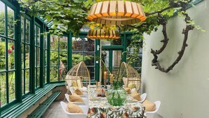 Ein Wintergarten mit Esstisch, umgeben von grünen Wänden und einer Glaskuppel.