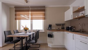 Une cuisine moderne avec des meubles blancs, un plan de travail en bois et un coin repas comprenant une table et des chaises.