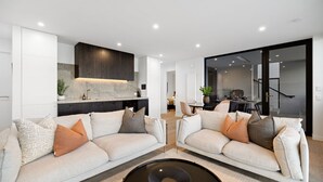 A modern living room with two sofas, a fireplace, and a dining area in the background.