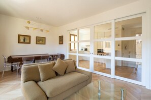 Una sala de estar moderna con un sofá, sillas traslúcidas, un piano y una mesa de vidrio.