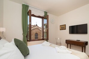 Una habitación de hotel con una cama, un televisor, un escritorio y una ventana con cortinas.