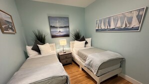 A bedroom with two beds, a nightstand with a lamp, and two paintings on the walls. - Recently Renovated 2 Bed 1 Bath (Dog Friendly) Apartment in the Broadway Neighborhood (Newport)