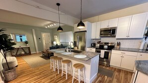 A modern kitchen with white cabinets, stainless steel appliances, and a central island with stools. - Recently Renovated 2 Bed 1 Bath (Dog Friendly) Apartment in the Broadway Neighborhood (Newport)