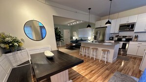 A modern kitchen with a central island, white cabinetry, and a stainless steel refrigerator. - Recently Renovated 2 Bed 1 Bath (Dog Friendly) Apartment in the Broadway Neighborhood (Newport)