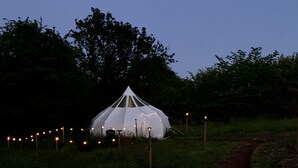 A white tent-like structure with string lights, surrounded by a grassy field and trees. - Star Gazing Bell Tent Farm Stay (Loughborough)
