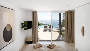 Camera moderna con un letto grande, una TV a schermo piatto e vista sulla piscina e sul paesaggio.