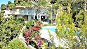 Una casa moderna con piscina, immersa nel verde e circondata da piante fiorite.