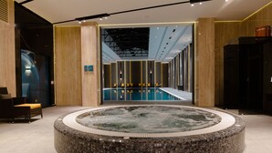 Un vestíbulo moderno con hidromasaje central, zona de estar y vistas a la piscina.