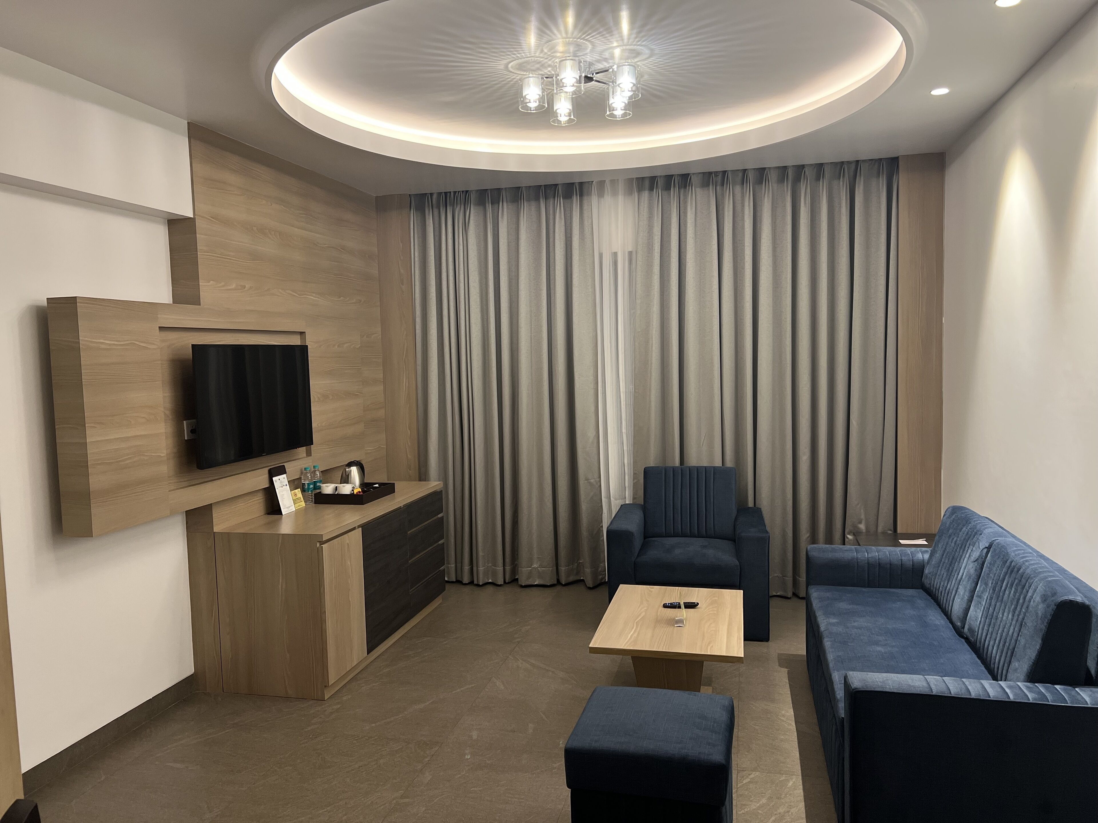 A modern living room with a flat-screen TV, a sofa, a coffee table, and a chair.