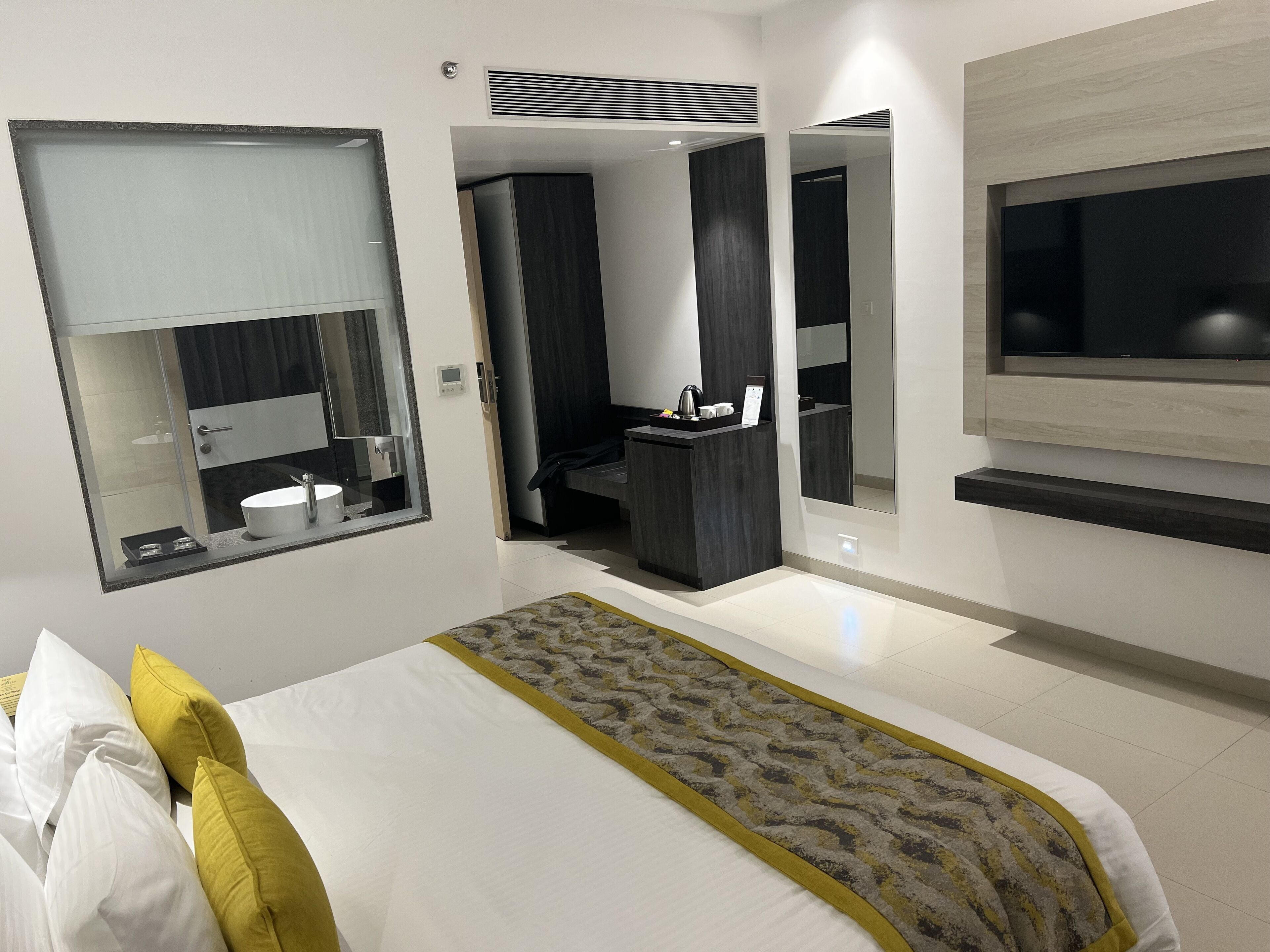 A modern hotel room with a large bed, a TV mounted on the wall, and a separate bathroom area.